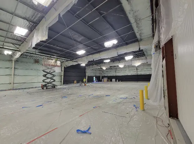 Cold storage area interior with insulation, pipes, and lights.