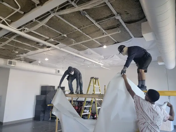 Team members securing insulation material in a San Francisco research lab during renovation.

              