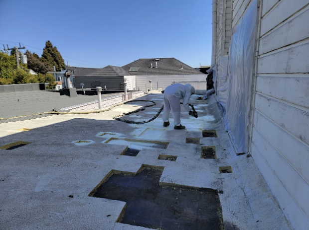  Workers applying spray foam insulation to a flat roof on a sunny day in San Jose, improving waterproofing and insulation properties.  

              