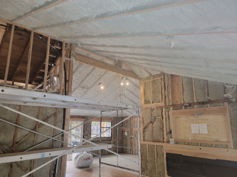  Interior view of a large custom home under construction with spray foam insulation applied to the roof and walls. 