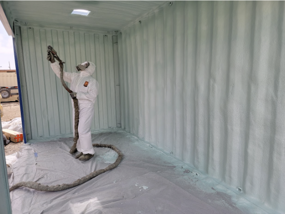 Technician applying spray foam insulation inside a storage container. 