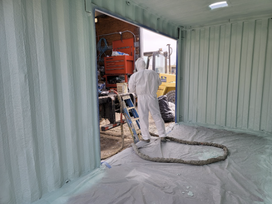  
         Worker in protective gear applying spray foam insulation to the walls of a medicine storage.


         