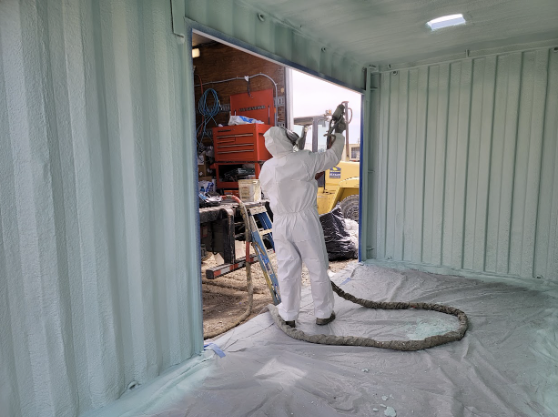  
         Technician applying spray foam insulation inside a storage container, designed for medicine storage in California.
         