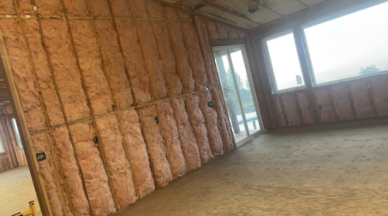  
         A room under construction with fiberglass insulation installed in the walls.
         