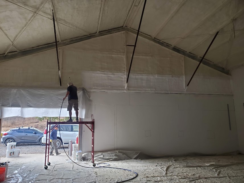  


                     Worker spraying insulation on the upper section of a large storage building.



                     