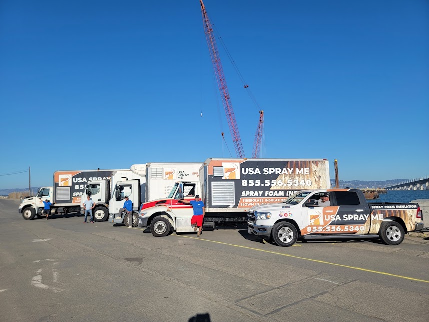  

                  USA Spray Me trucks and crew gathered at a job site near a construction crane.




                  