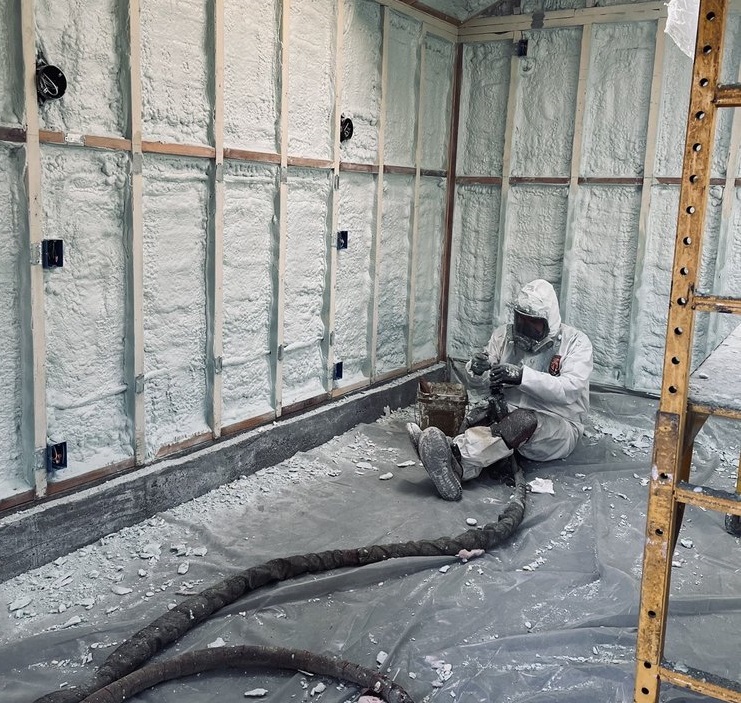  


                     Worker in protective gear applying spray foam insulation in a room with unfinished walls.





                     