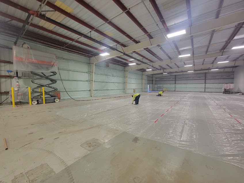  
               
               

               Workers preparing a large commercial warehouse for spray foam insulation with protective plastic sheeting on the floor.
      
      
      
               