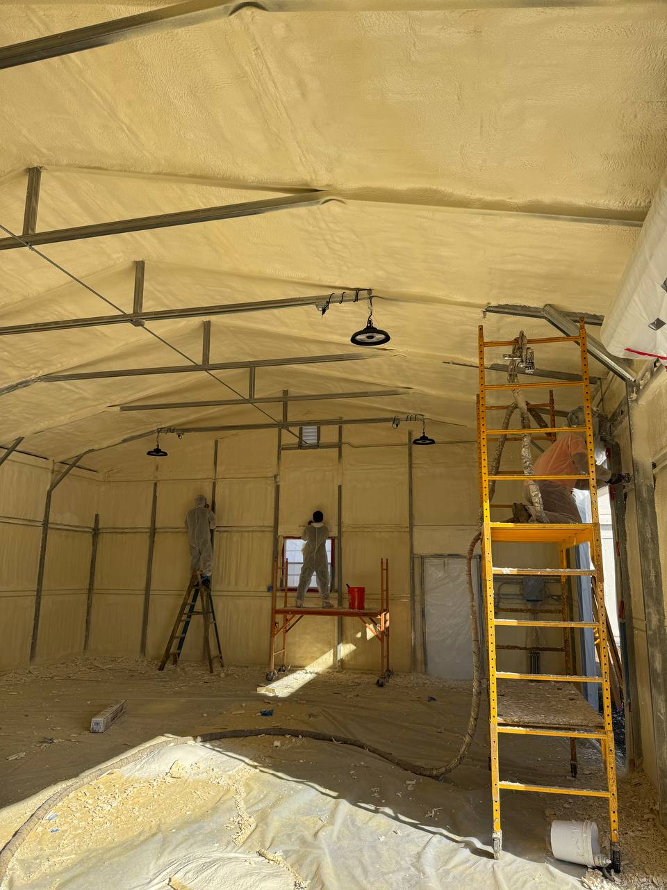 Interior of a residential building in Hayward with fiberglass insulation installed between wooden studs in walls and ceiling.