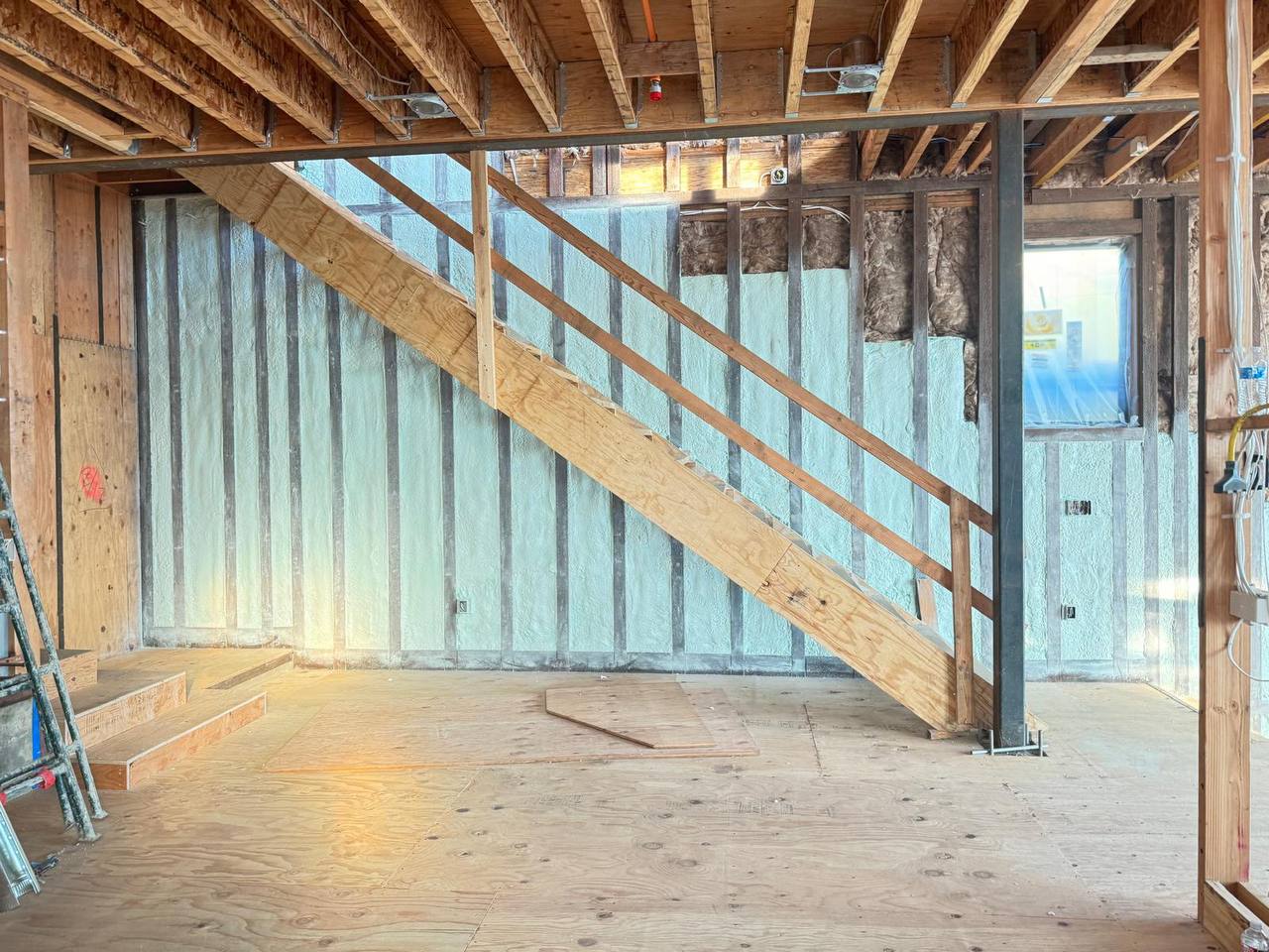 Rooftop of a commercial building in Palo Alto with spray foam roofing insulation applied to the surface and parapet walls, HVAC equipment and electrical cables visible.