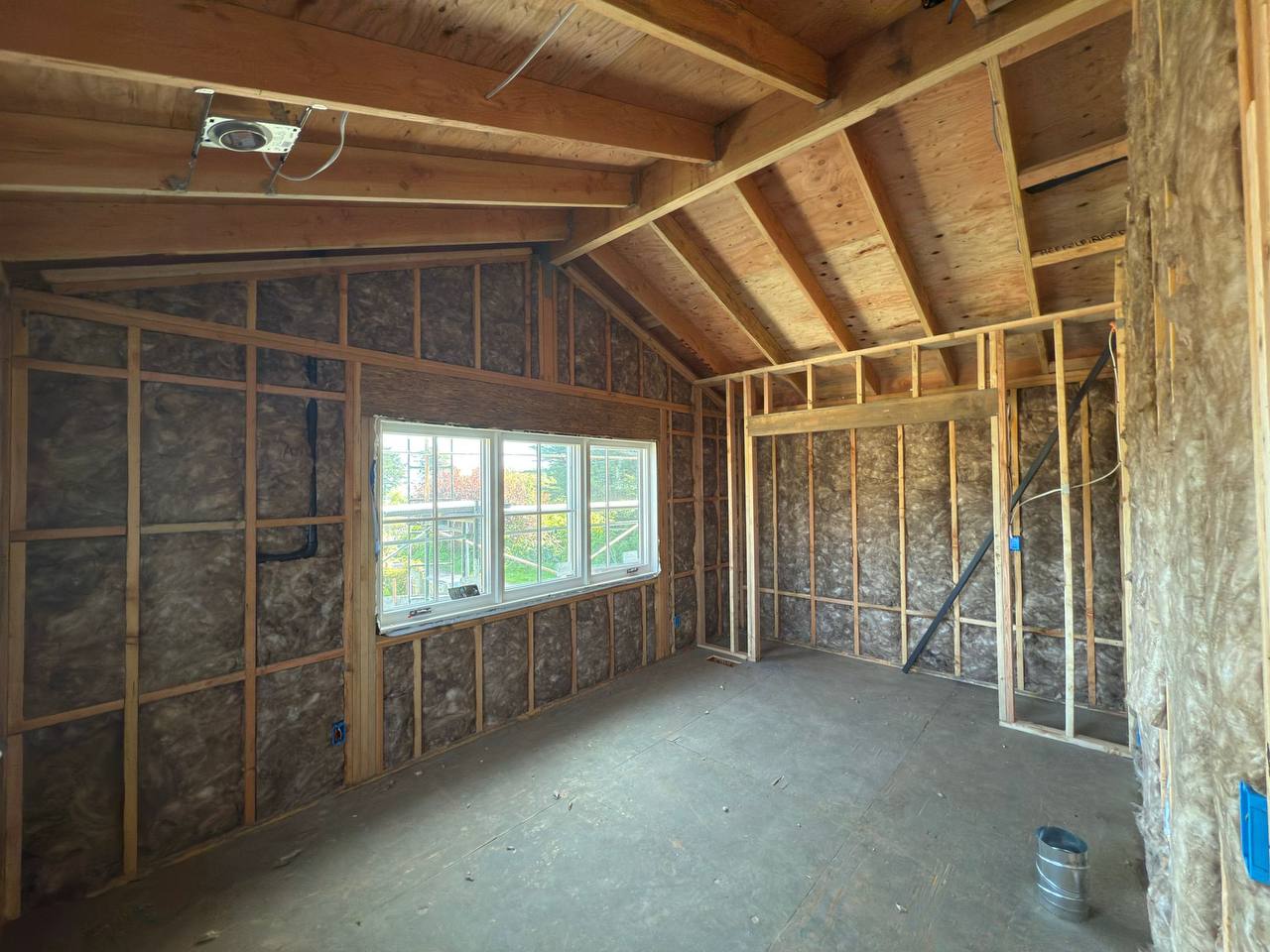 Workers in protective suits applying spray foam insulation to the interior walls of a commercial metal building in Palo Alto, with scaffolding and ladders visible.