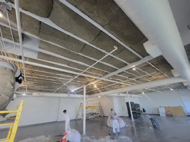 Workers installing insulation in the ceiling of a research lab in San Francisco, improving thermal efficiency.