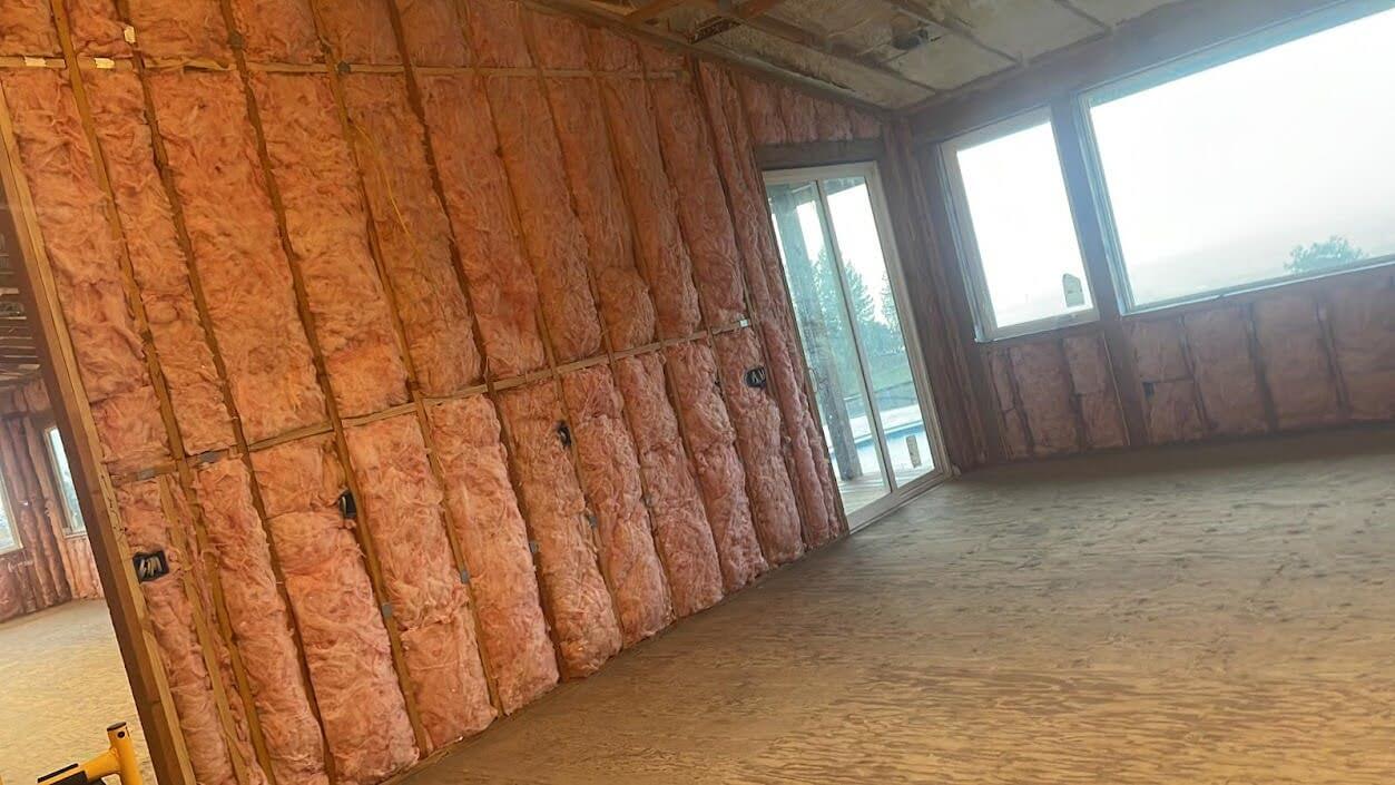 A room under construction with fiberglass insulation installed in the walls.