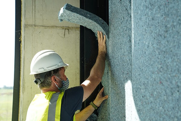 Installation of cotton (denim) wall insulation.
