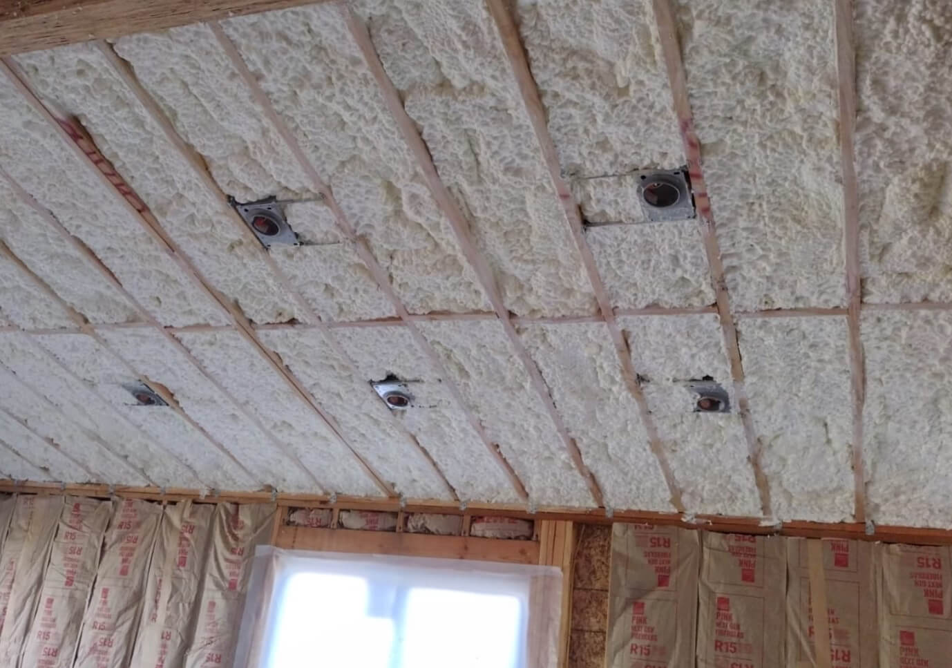 Application of spray foam insulation in between wooden wall studs