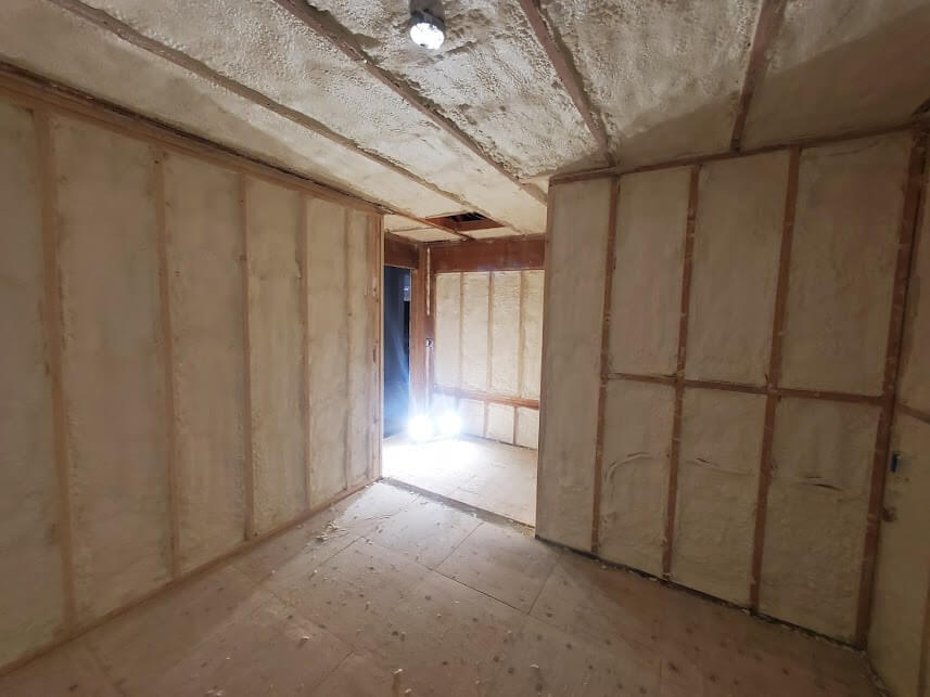 Room with spray foam insulation applied to walls and ceiling, ensuring airtight sealing.