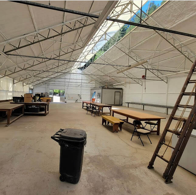 Interior view of an insulated agricultural structure with tables and equipment.