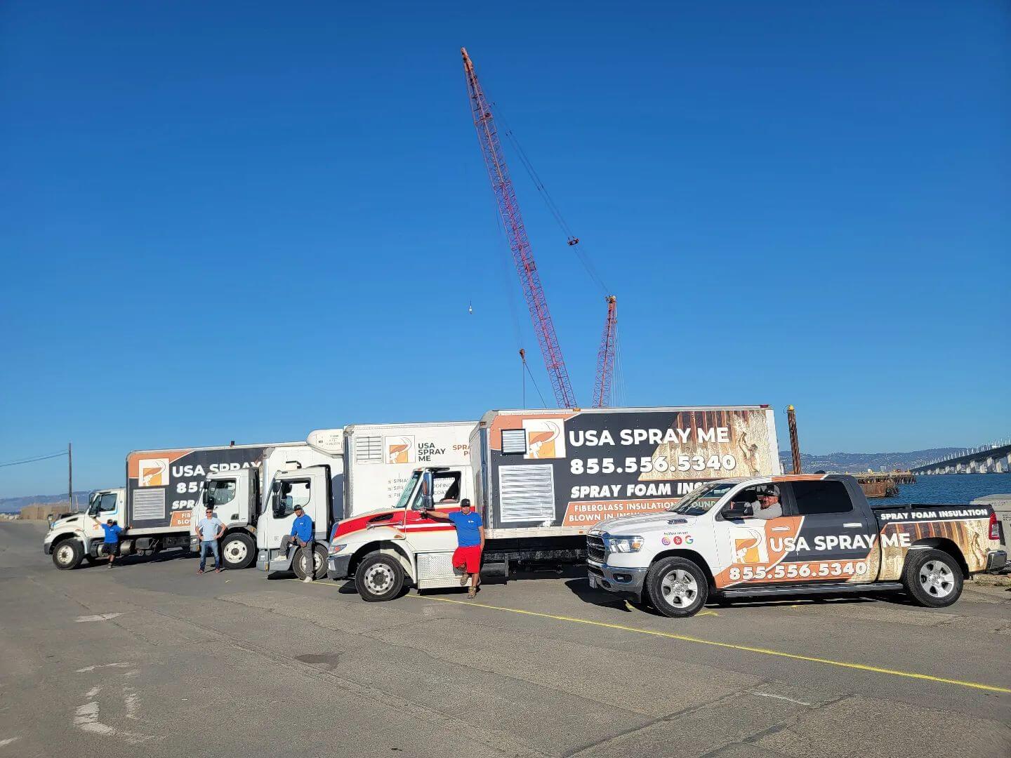: Fleet of USA Spray Me trucks and vans ready for insulation projects near the waterfront.