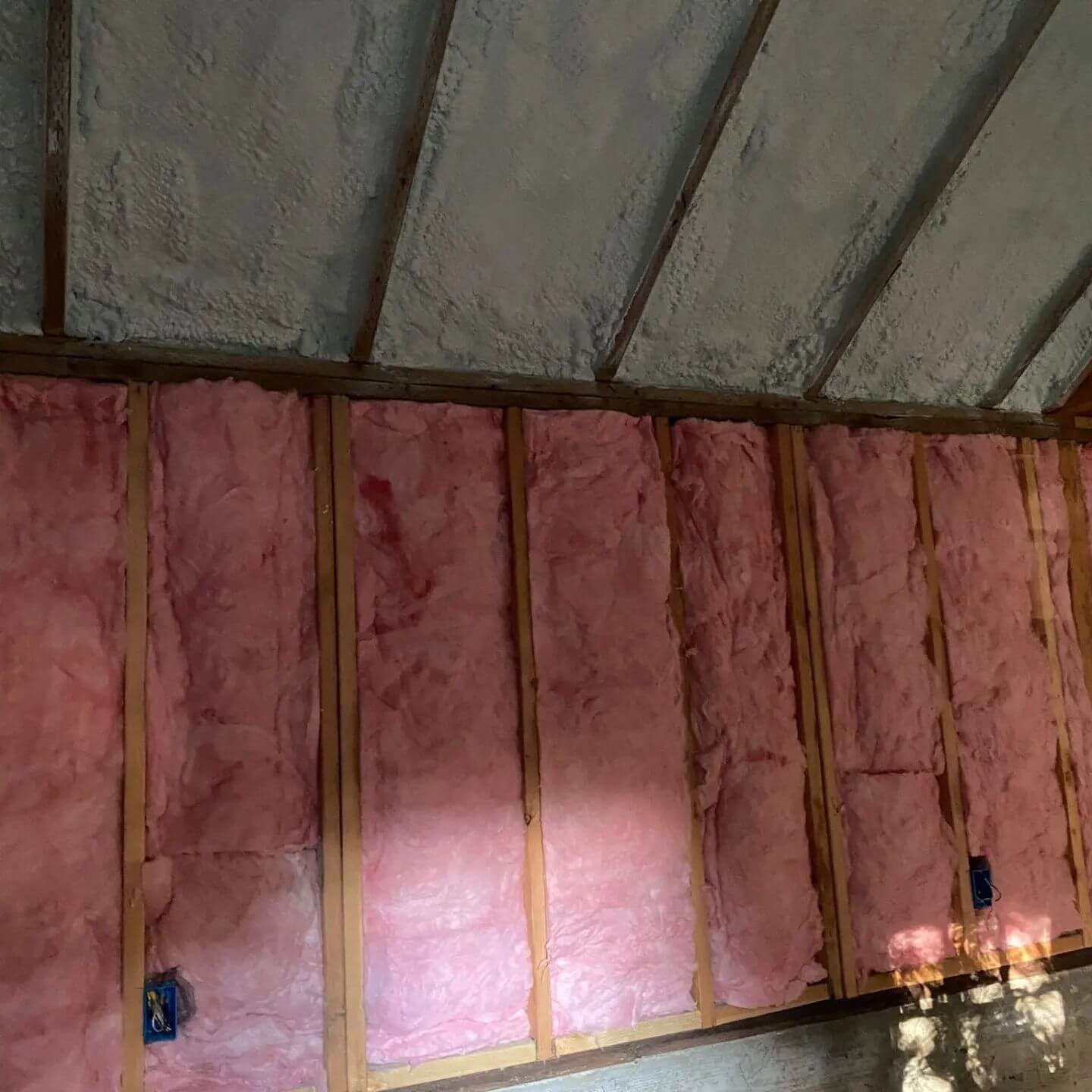 Wall with both spray foam and fiberglass insulation in a building.