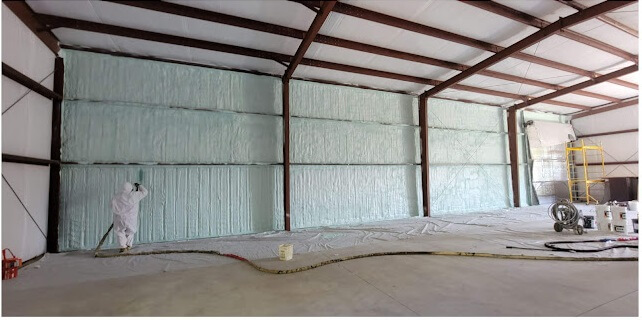 USA Spray Me technician applying spray foam insulation on a commercial building wall.