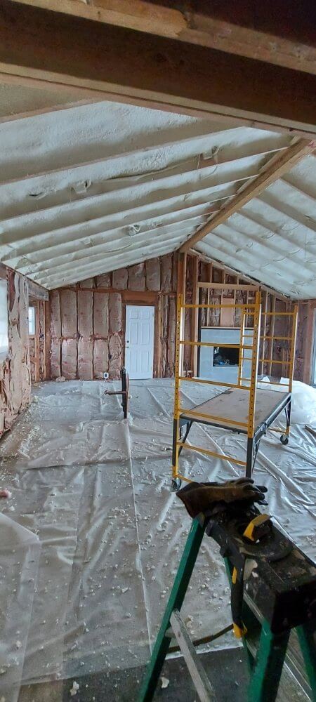 Interior room with spray foam insulation applied to the ceiling and walls.