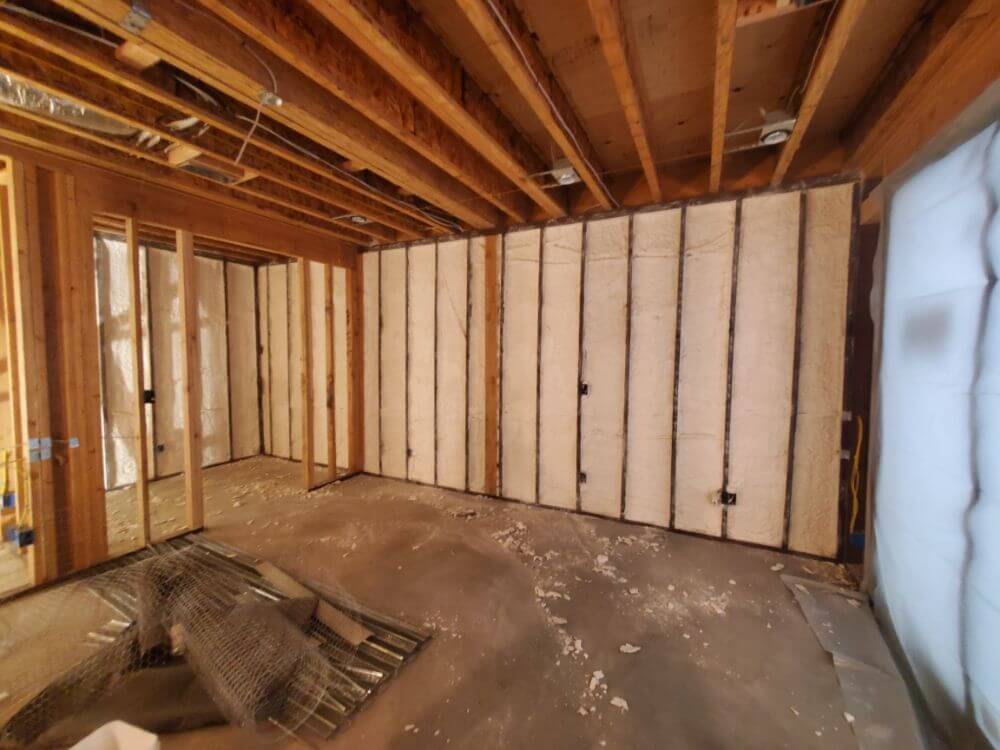 Unfinished room with Spray Foam insulation applied between wall studs.