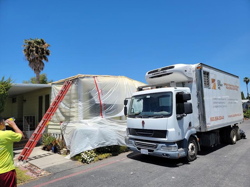  A truck with USA Spray Me branding parked next to a residential property. 