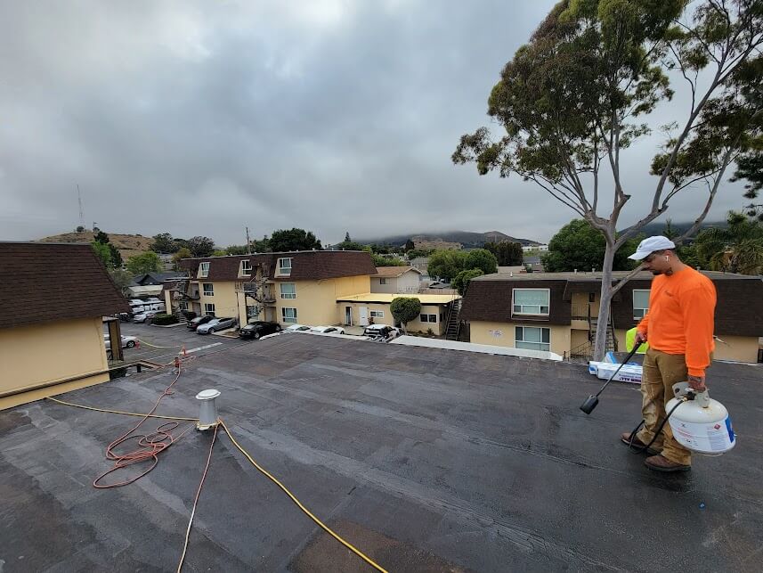  Worker applying SPF insulation to a Fresno roof. 
