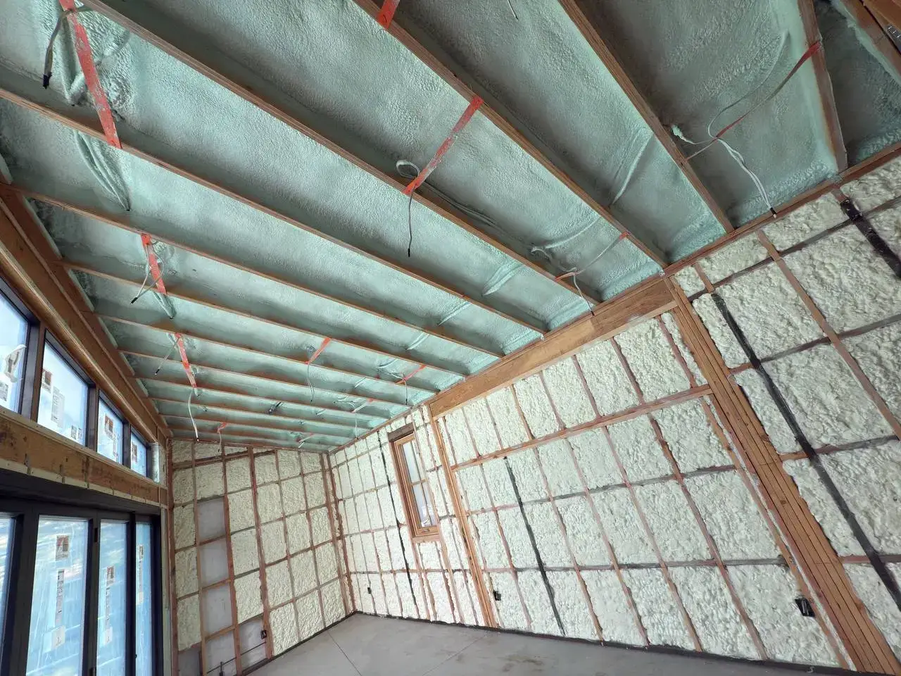 Interior of a building under construction in Walnut Creek with spray foam insulation applied to walls and ceiling between wooden studs.